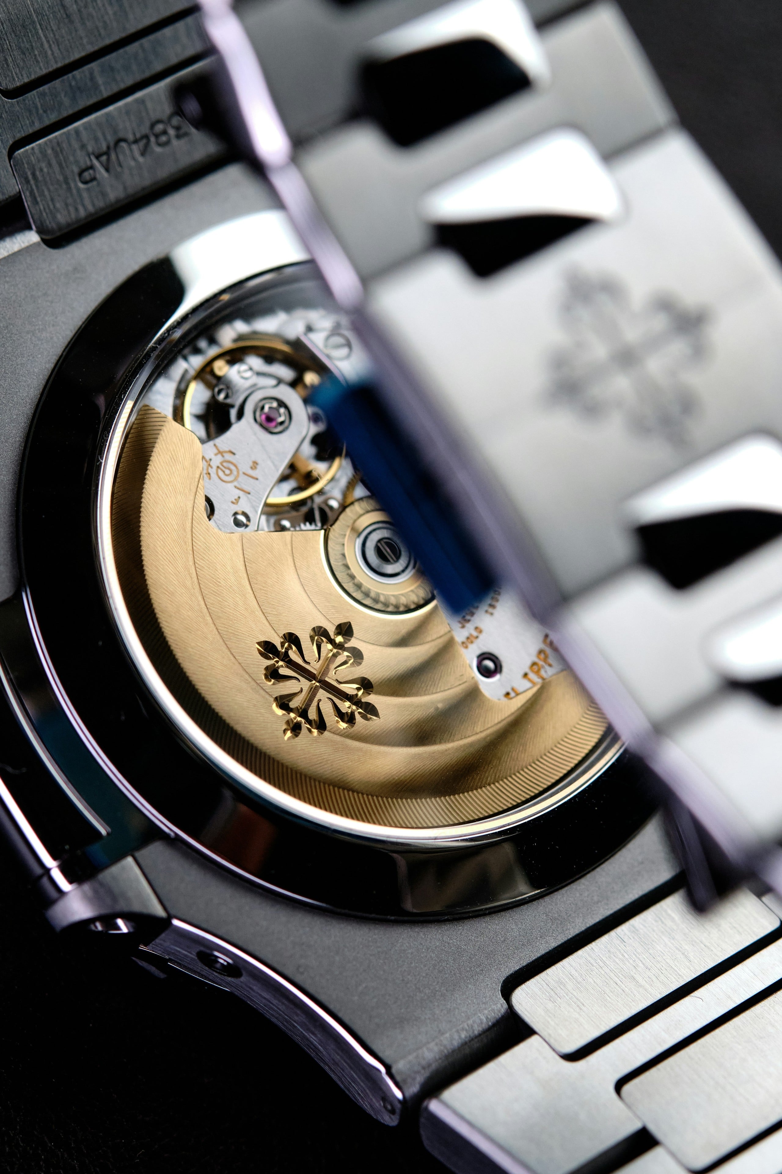 Sapphire caseback of a steel sports watch showing a gold rotor