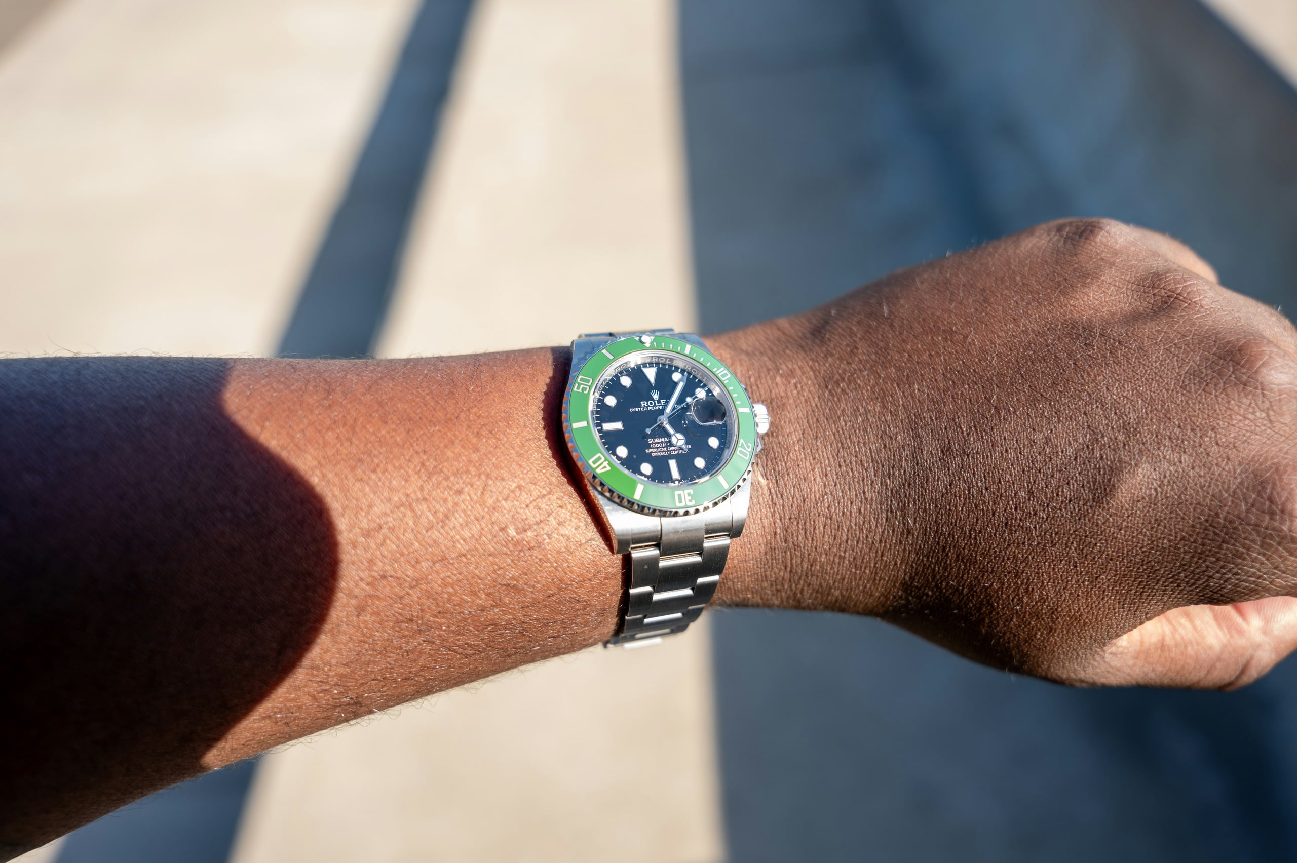 Rolex Submariner Date with green ceramic bezel worn on the wrist in sunlight