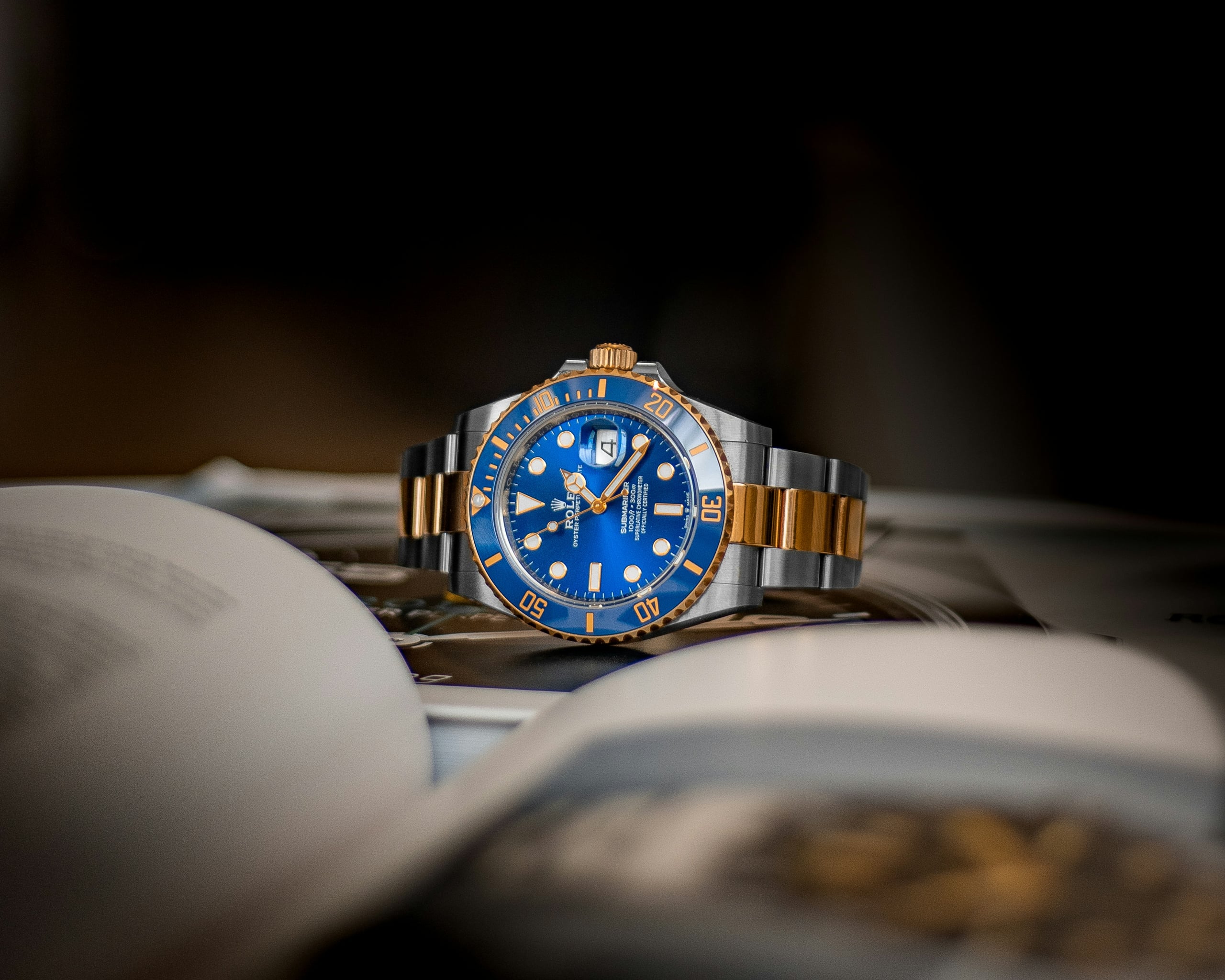 Rolex Submariner Date in steel and gold with royal blue dial and bezel, resting on an open book